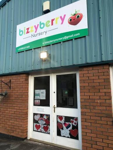 The front entrance of Bizzyberry Nursery — the strawberry sign above glass double doors decorated with the children's heart and dalmatian artwork