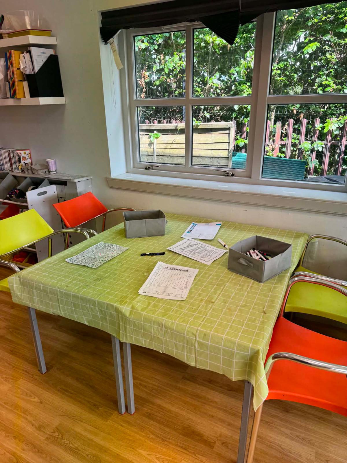 A craft table by the window with colouring and word-search sheets