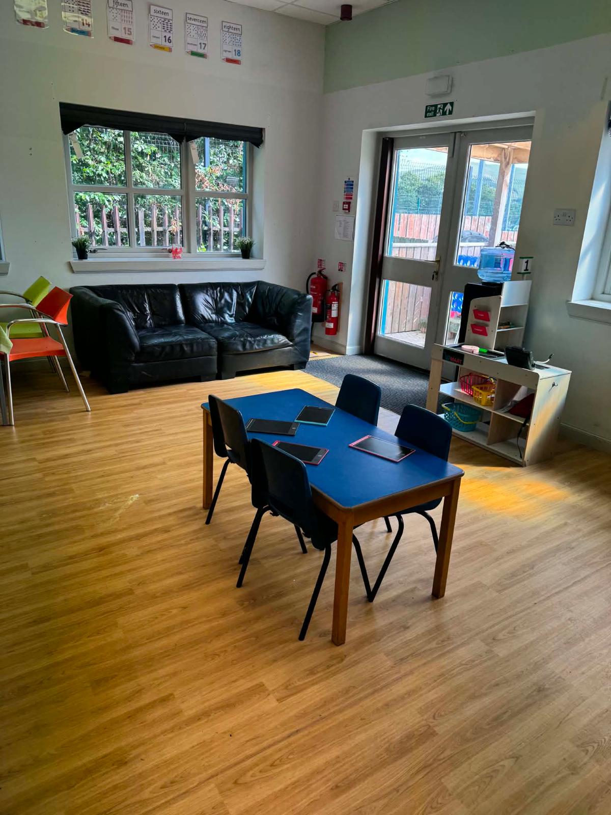 A comfy sofa corner with tablets on the table and a door out to the garden