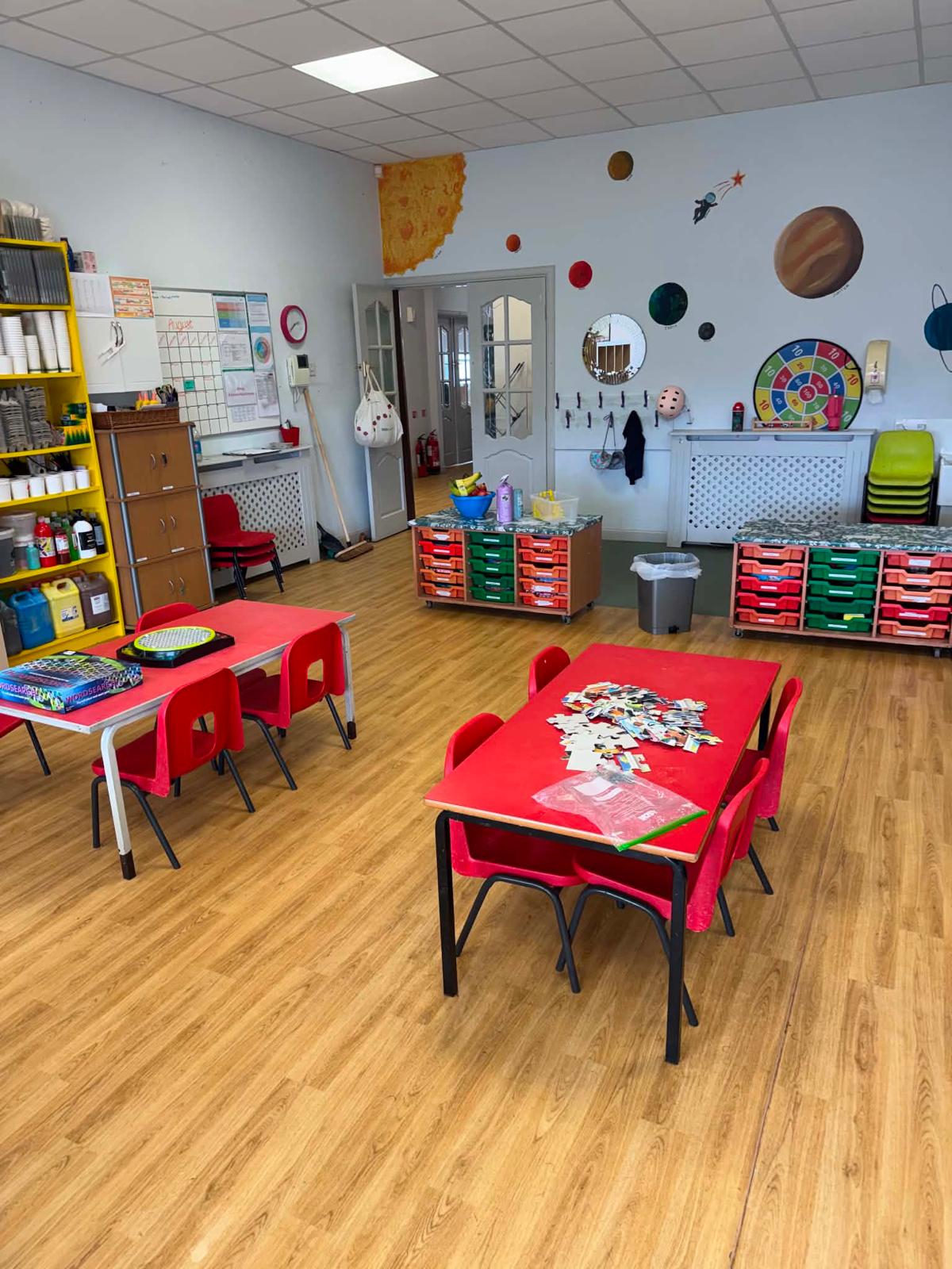 A bright, spacious room with a space-and-planets wall display and games tables