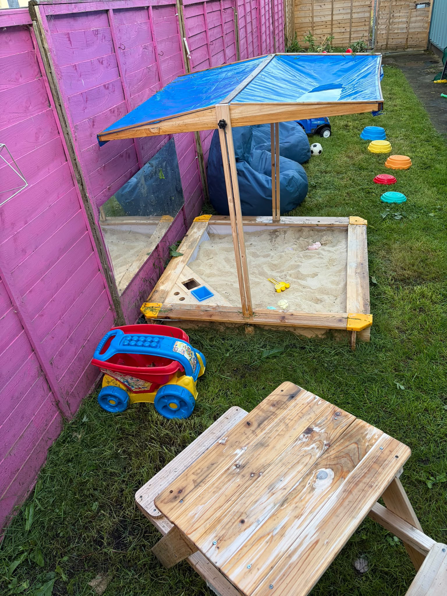 A covered sandpit and picnic bench in the baby room's garden