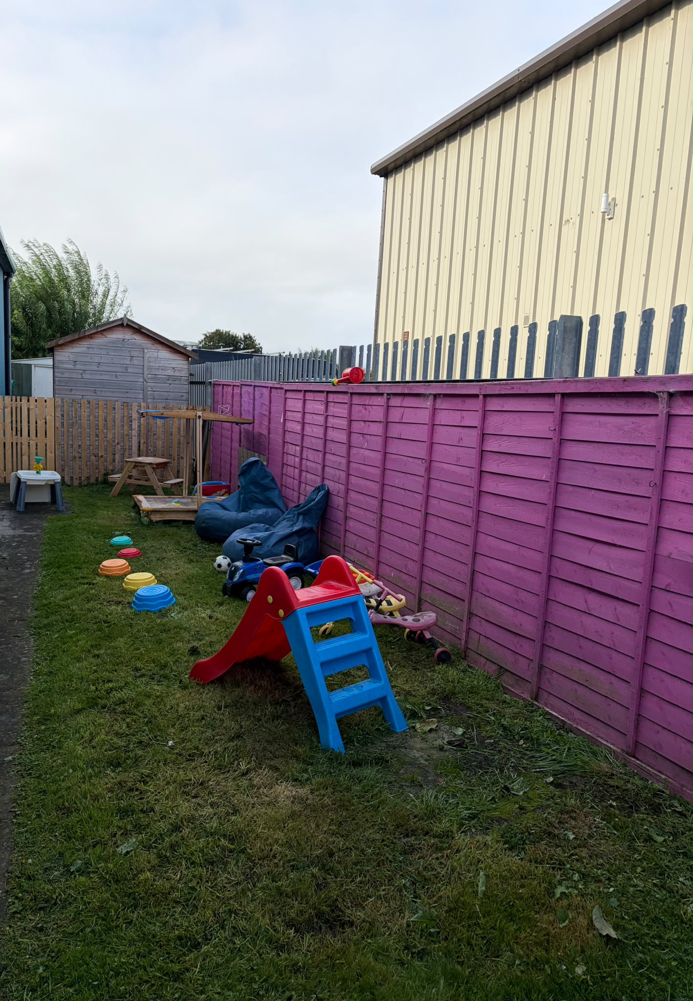 The baby room's own garden — slide, stepping stones, sandpit and ride-on toys