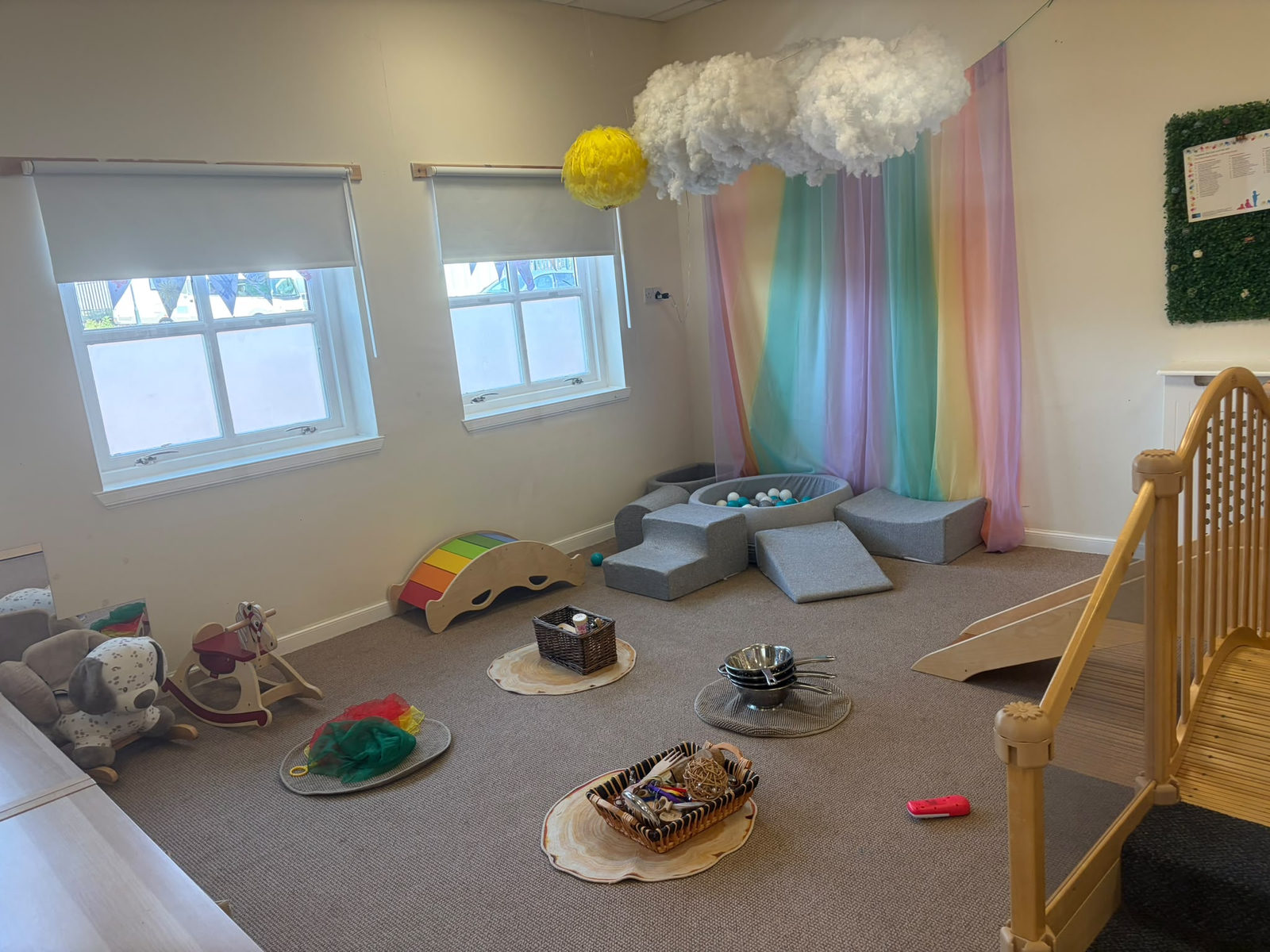 The Jelly Babies soft play corner — ball pit, climbing blocks and a rainbow canopy under a cloud