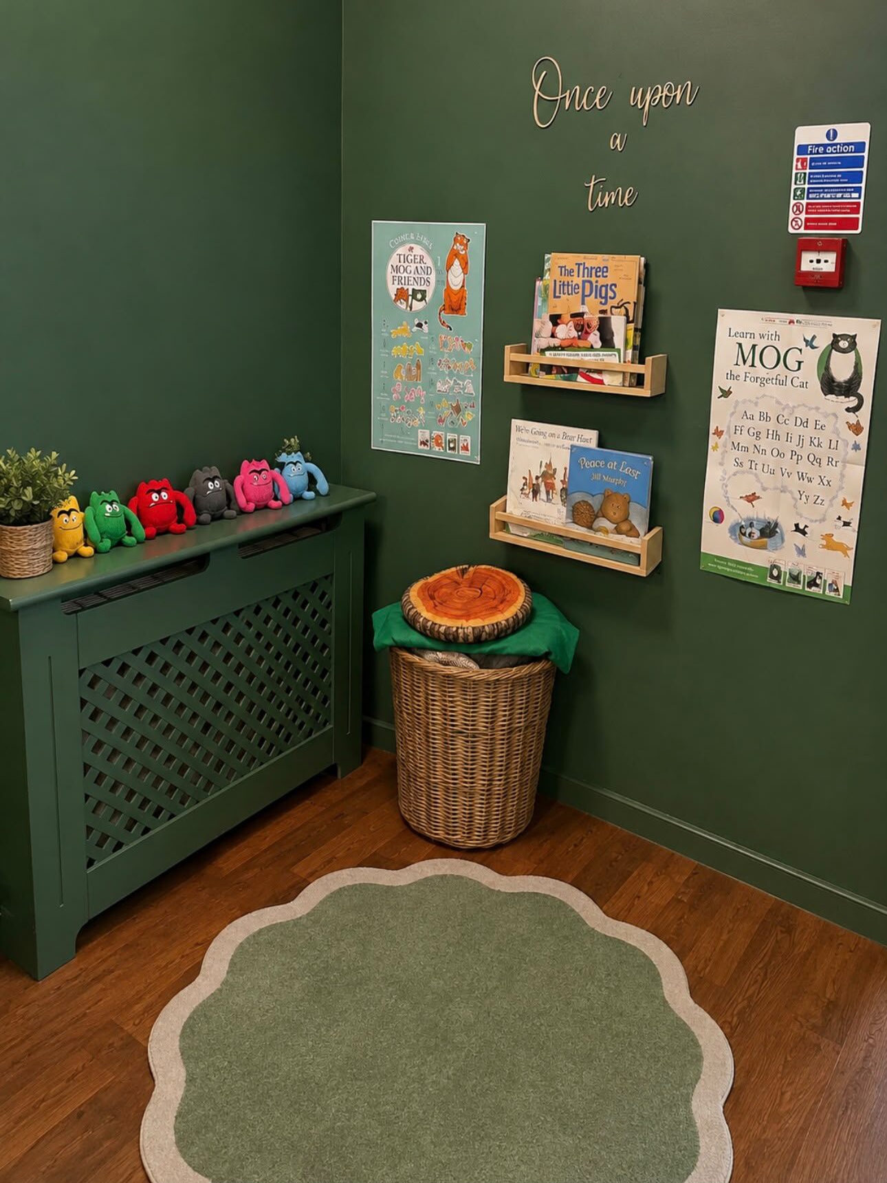 The book corner with green walls, 'Once upon a time' lettering, a reading basket and picture books on ledges