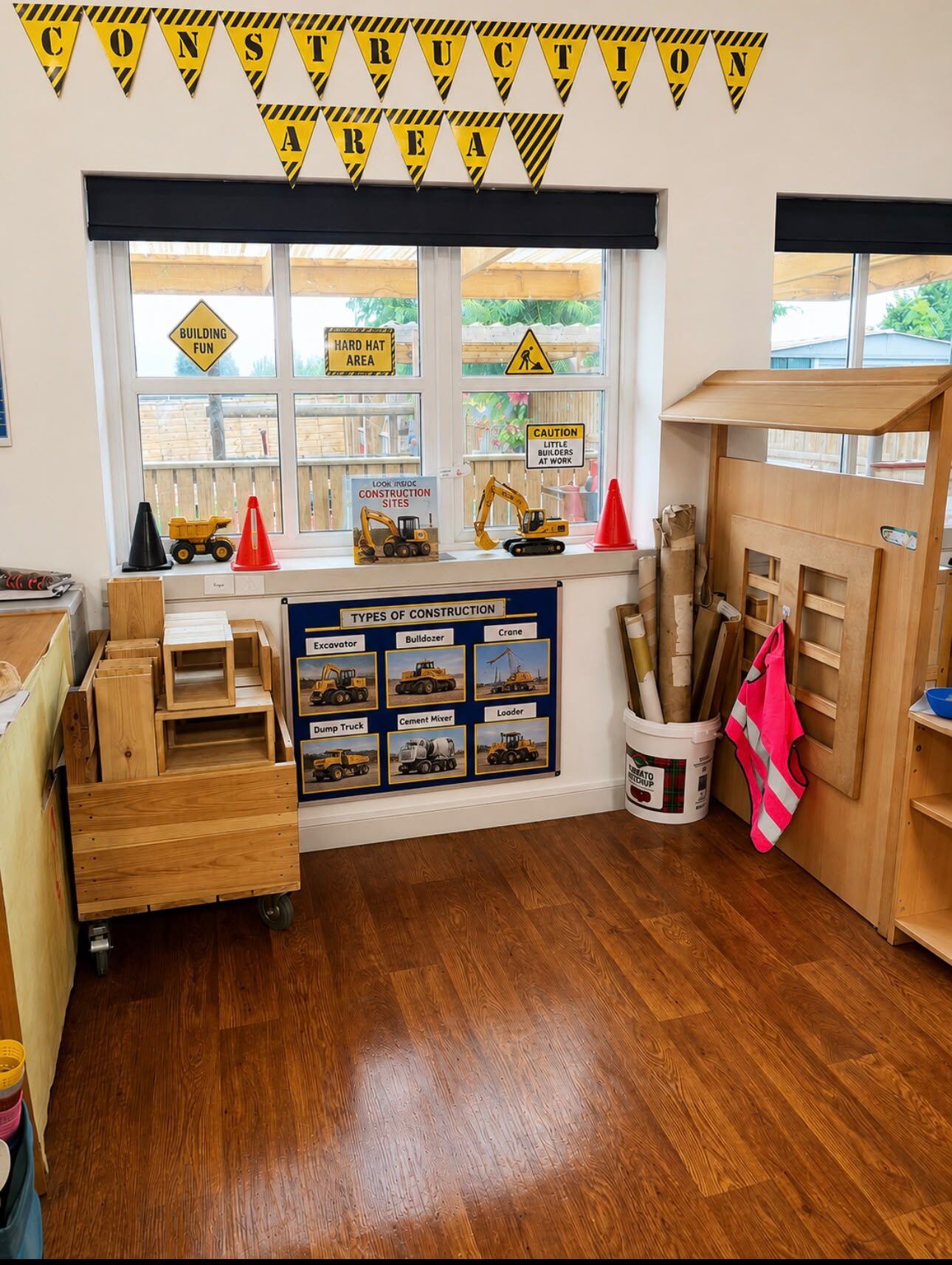 The construction area — a 'Construction Area' banner, hard-hat and 'little builders at work' signs, wooden blocks, diggers and a types-of-construction poster