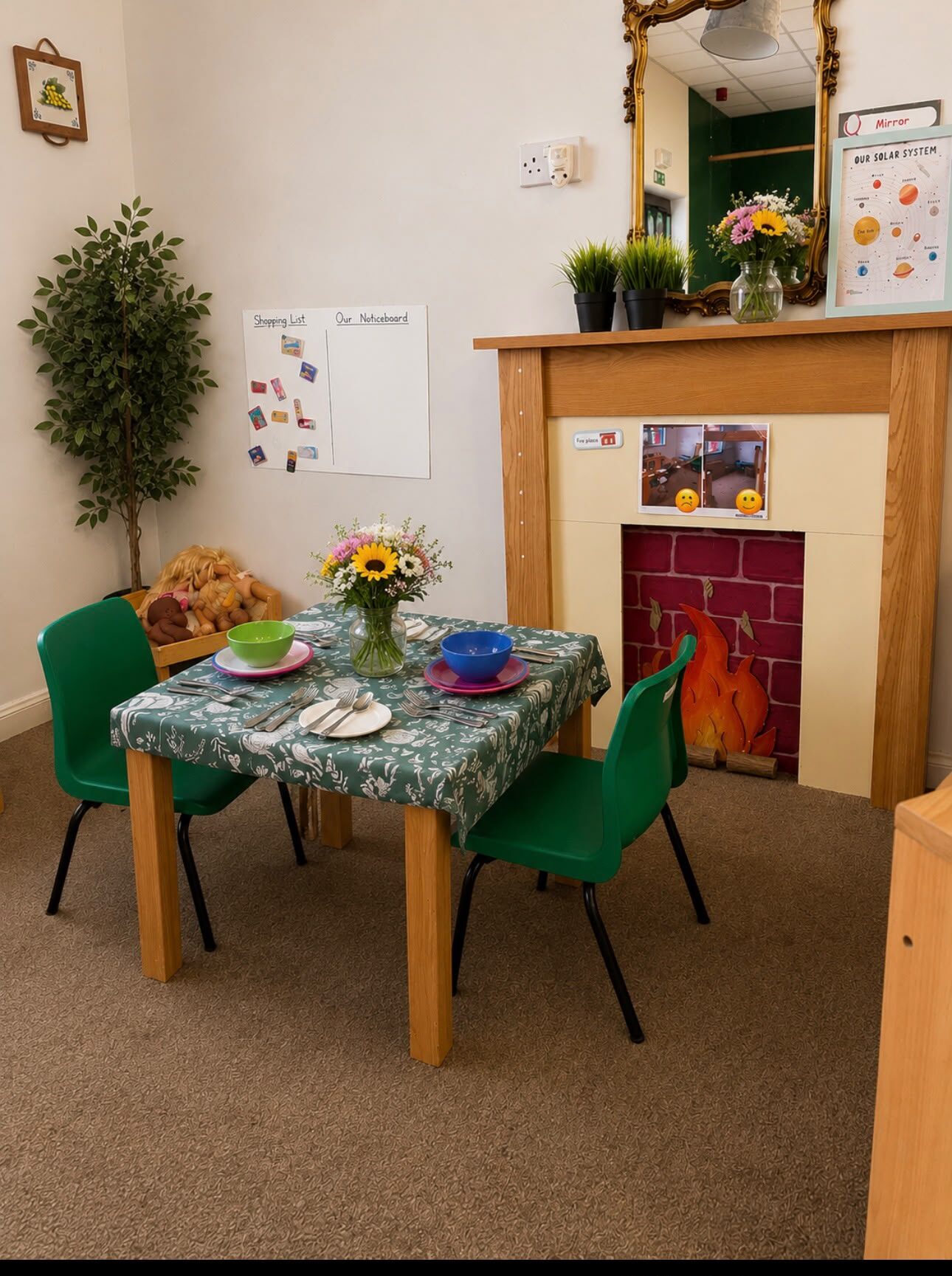The home corner — role-play with a pretend fireplace, a set dining table and a dolls' crib