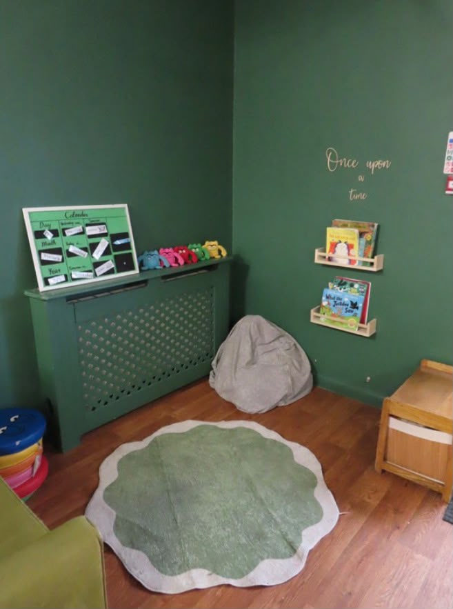 Story corner with green walls, book ledges and a beanbag under 'Once upon a time' lettering