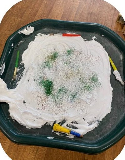 Messy play tray with shaving foam, brushes and glitter