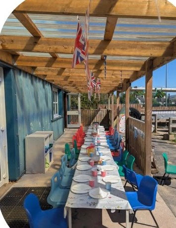 Party table set for lunch under the outdoor pergola, bunting overhead
